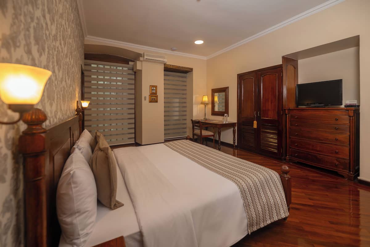 A hotel room with a bed, a desk, a television, and a wardrobe.