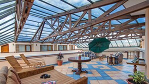 A spacious outdoor area with a glass ceiling, wicker furniture, and a variety of seating options. - Hotel Patio Andaluz (Quito)