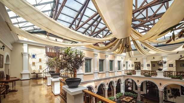 A spacious atrium with high ceilings, large windows, and a central staircase. - Hotel Patio Andaluz (Quito)