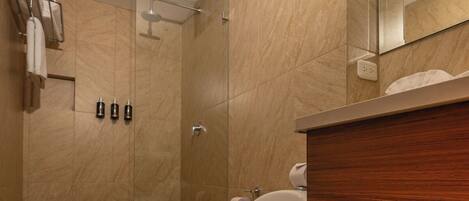 A bathroom with a toilet, a shower, and a sink.