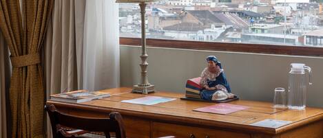 A wooden desk with a lamp, a figurine, and a water bottle.