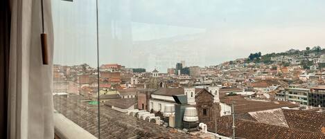Vista de una ciudad desde una ventana, con edificios, una iglesia y una colina al fondo.