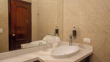 A bathroom with a wooden door, a white sink, a mirror, and two toiletries dispensers.