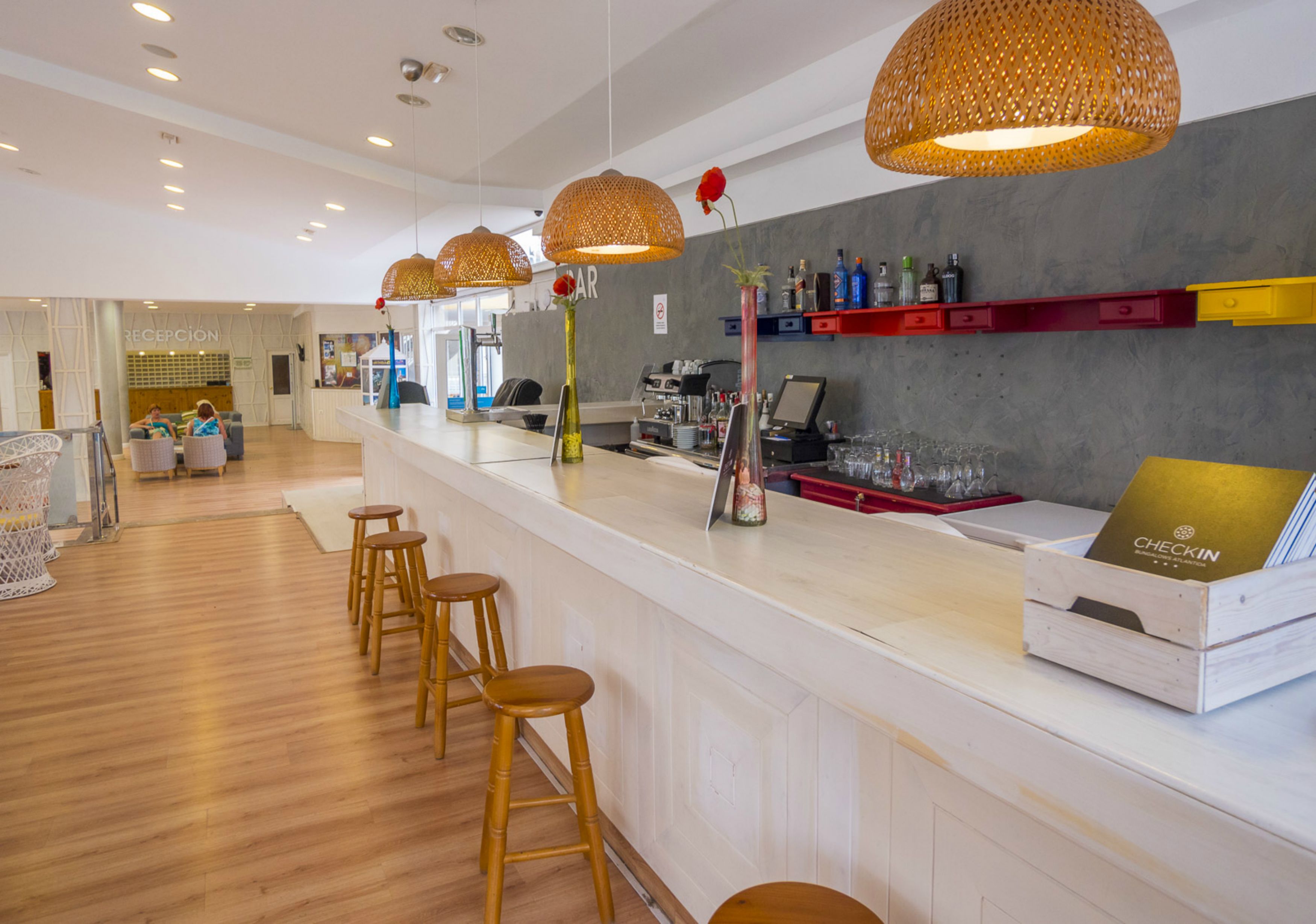 A reception area with a white counter, wooden stools, and a check-in desk.