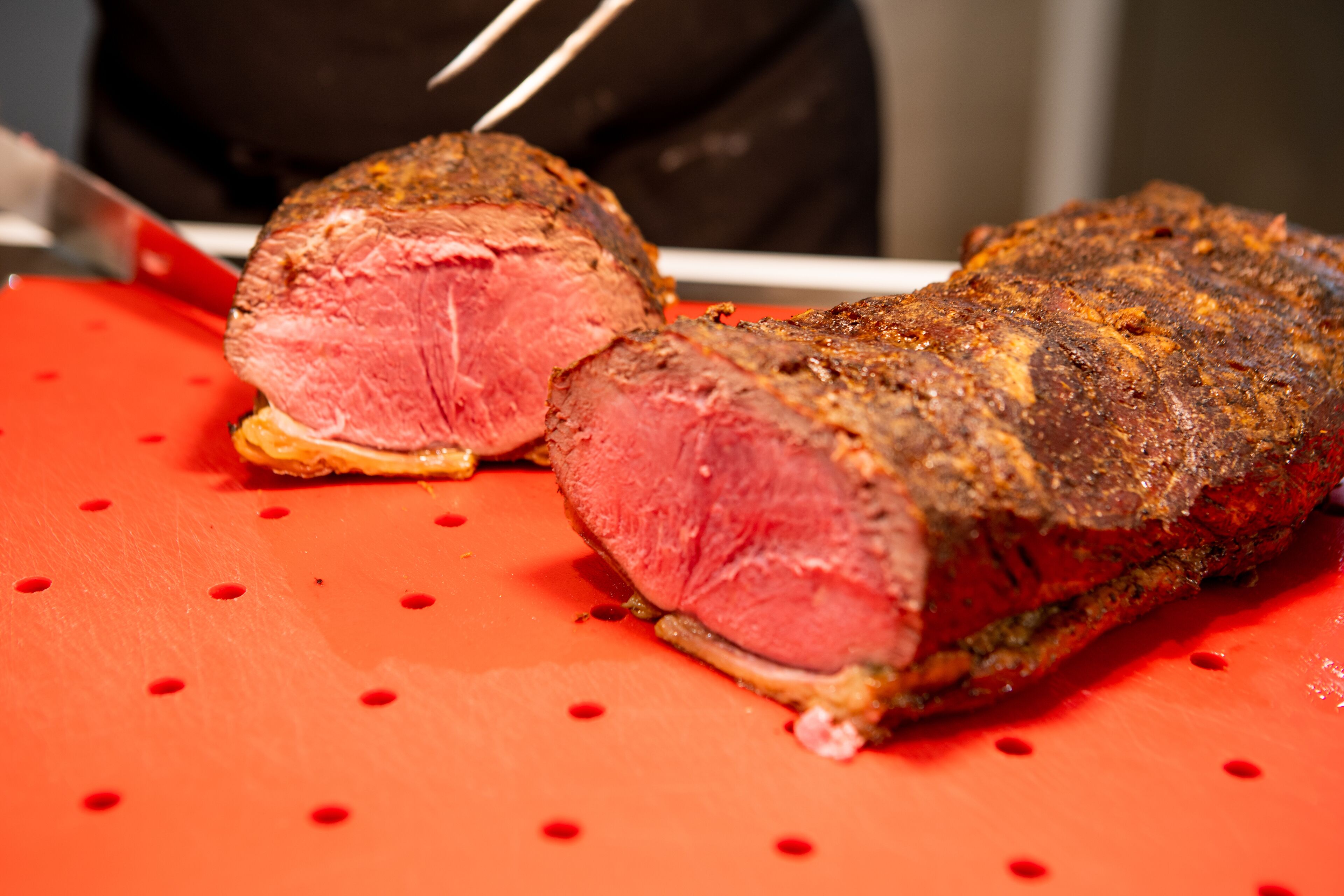 Un gran trozo de carne sobre una tabla de cortar roja.