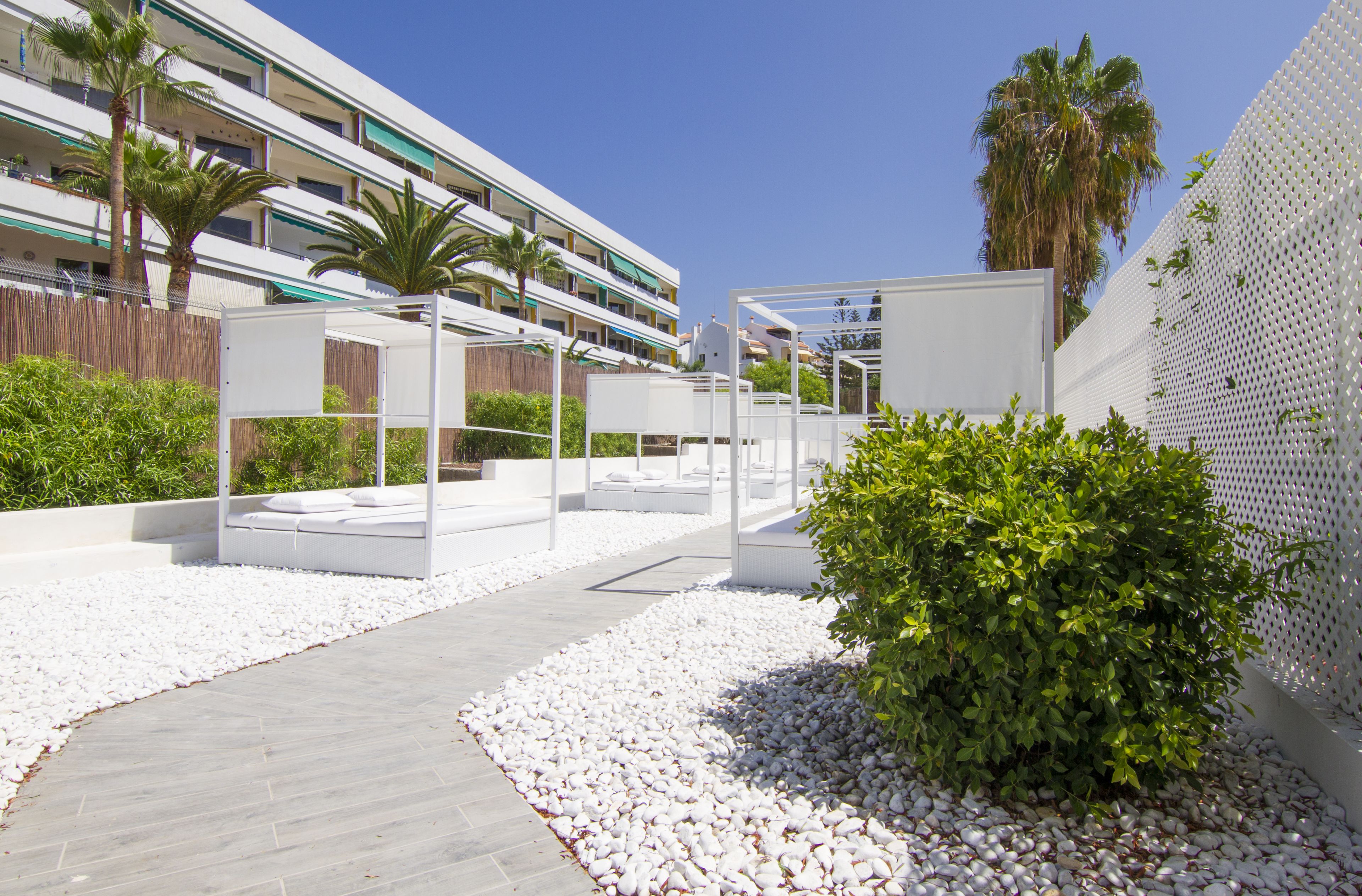 A modern outdoor area with white seating, a pathway, and a white fence.