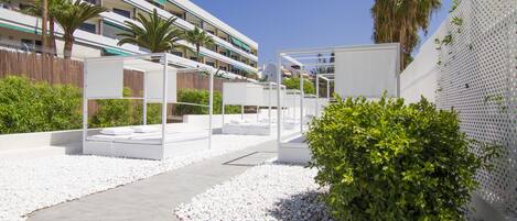 A modern outdoor area with white seating, a pathway, and a white fence.