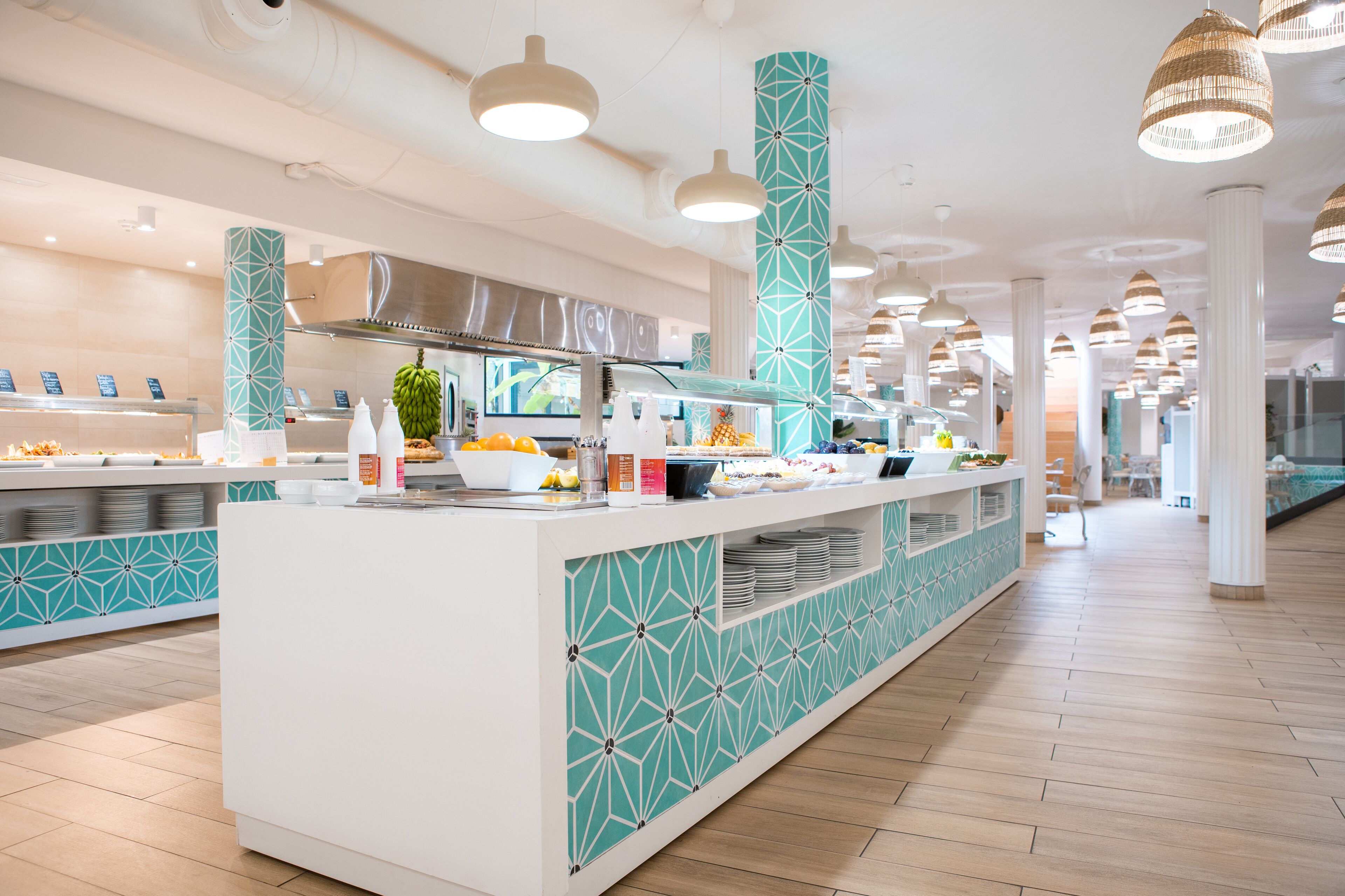A modern buffet area with a geometric tile pattern, a stainless steel range hood, and a variety of food items displayed.