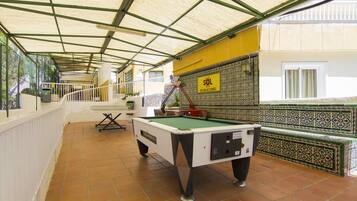 Une table de billard se trouve dans un espace abrité, doté d’un sol carrelé, d’une rambarde et d’un mur recouvert de carreaux décoratifs.