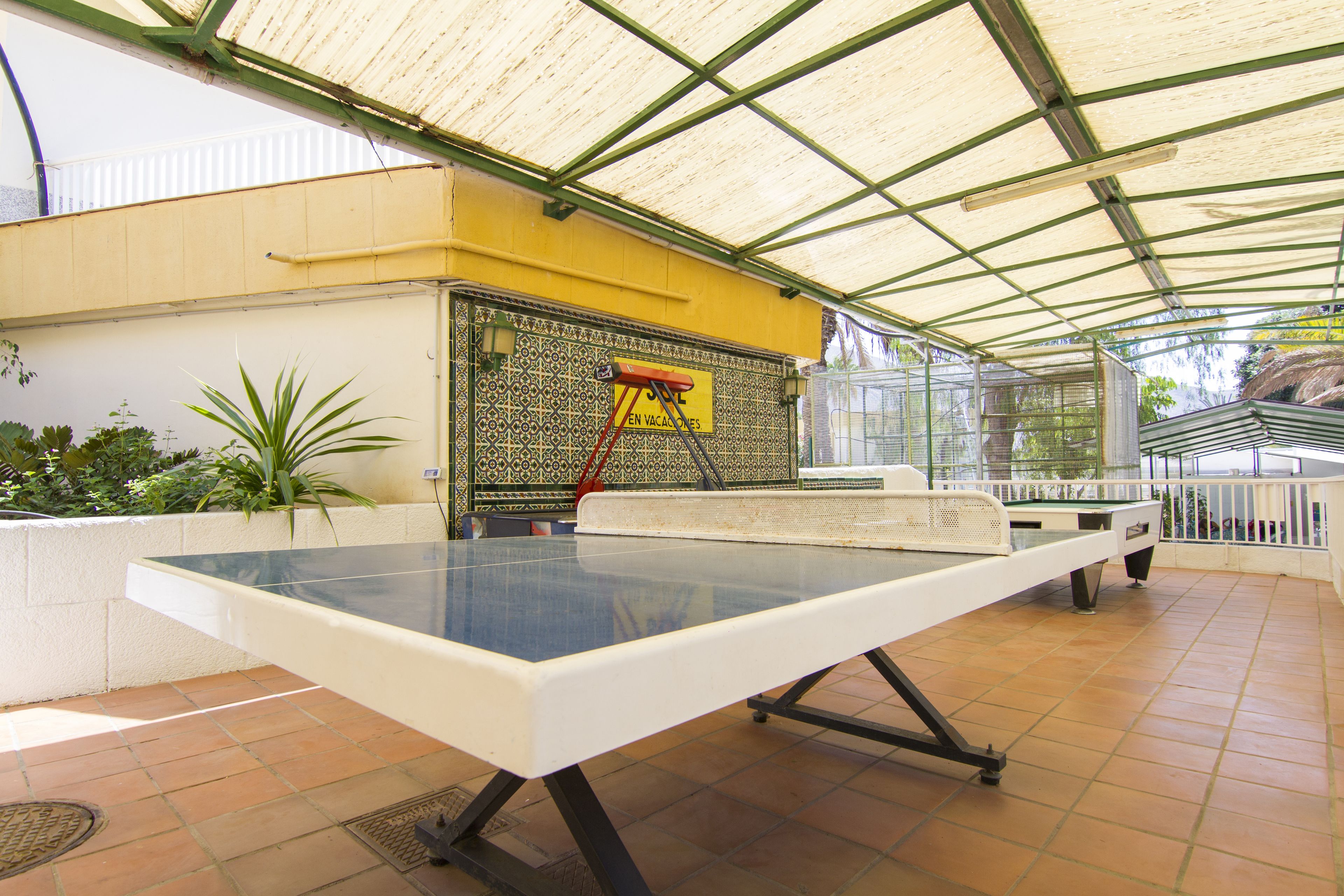 A covered outdoor area with a ping pong table, a ladder, and a decorative wall.