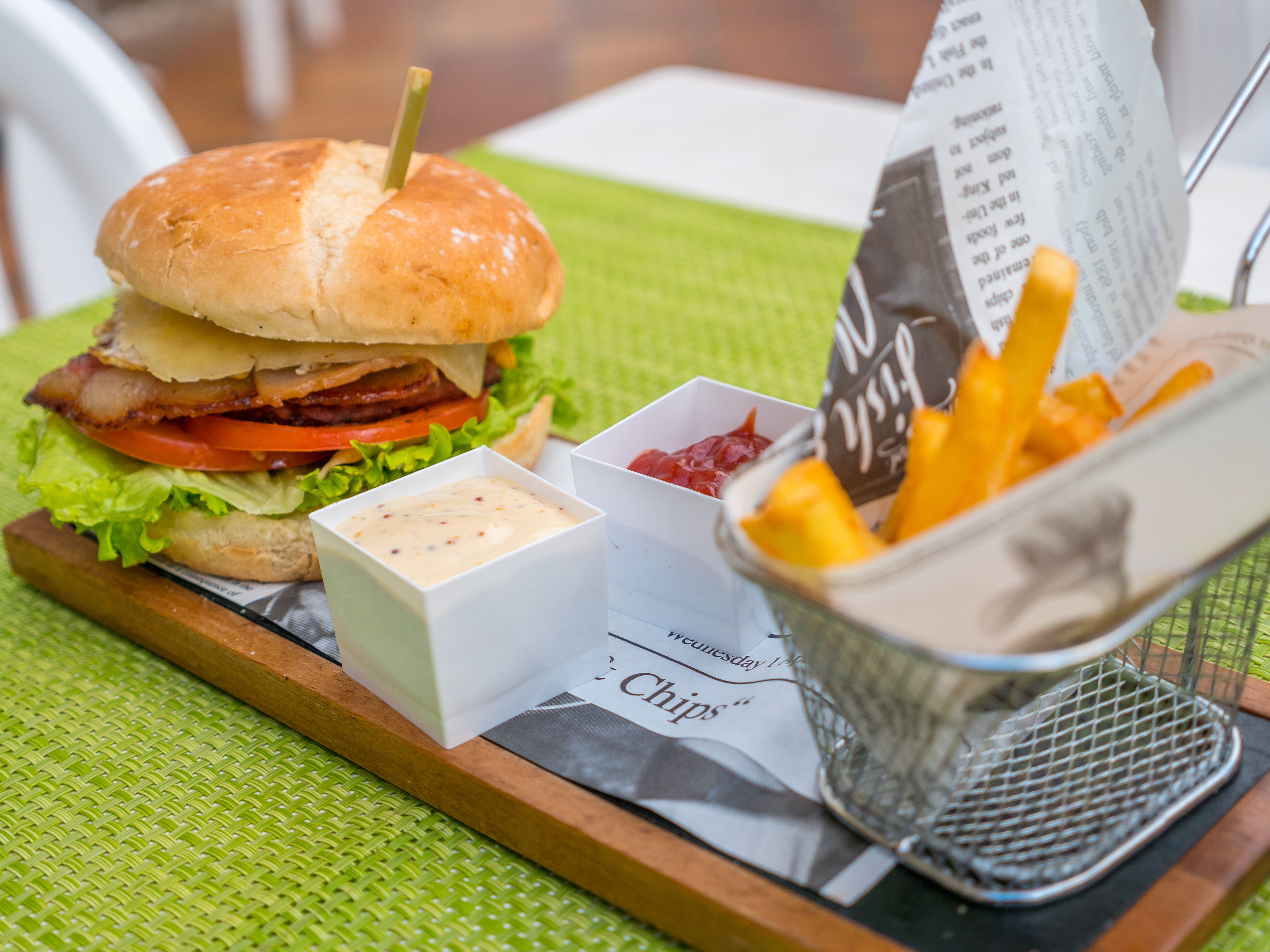 Een maaltijd bestaande uit een hamburger, friet en een drankje, geserveerd op een dienblad met een menukaart.