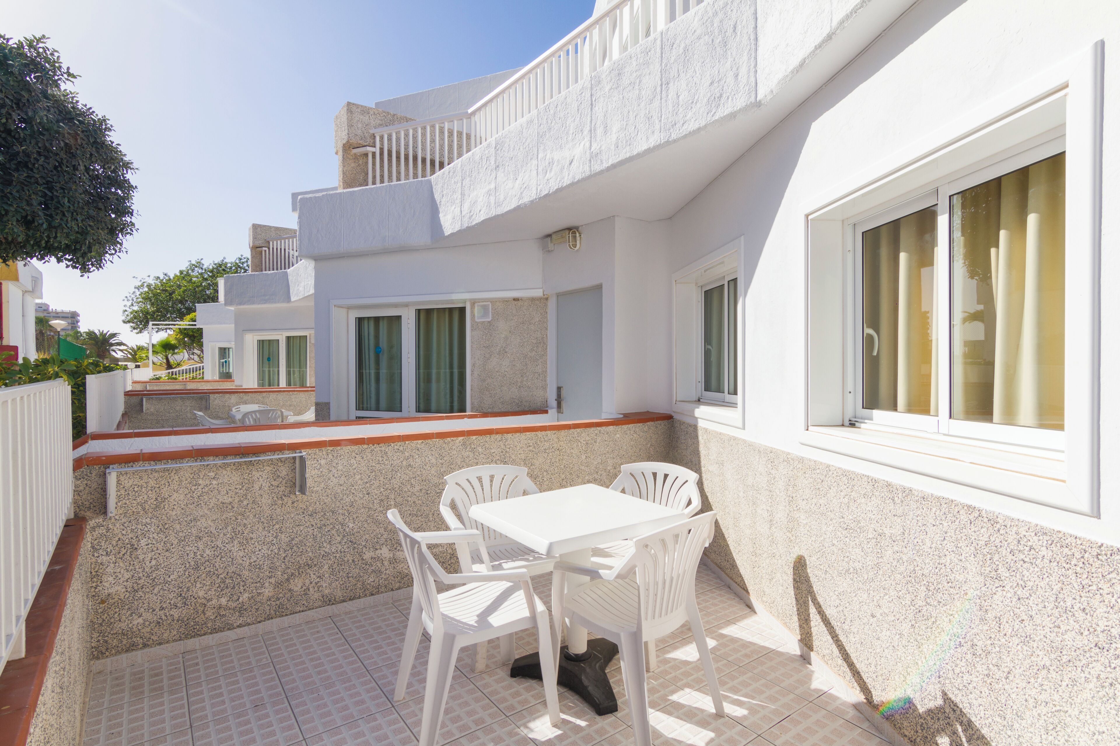 Una villa moderna con un patio, muebles blancos y una pequeña zona de piscina.