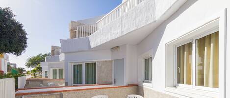 Una villa moderna con un patio, muebles blancos y una pequeña zona de piscina.