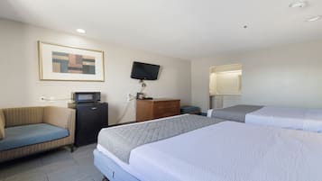 A hotel room with two beds, a sofa, a television, a microwave, and a desk.