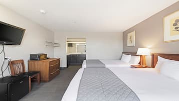 A hotel room with two beds, a television, a microwave, a dresser, and a bathroom visible through an open door.