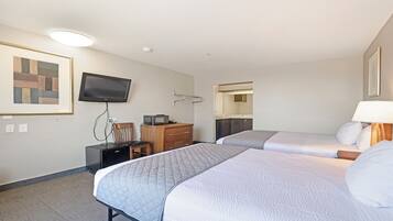 Habitación de hotel con dos camas, televisión, escritorio con silla, microondas y cómoda.