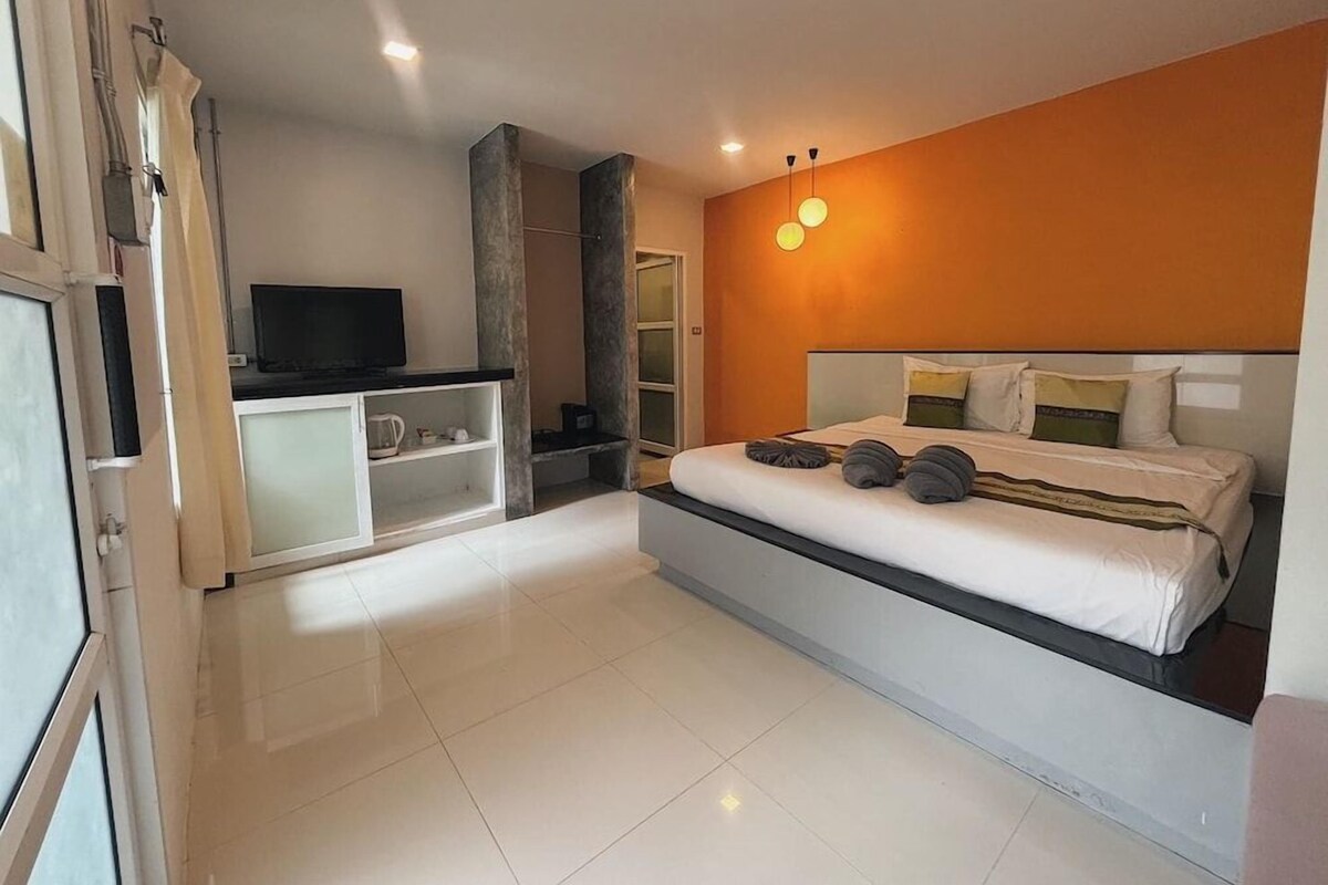 Un dormitorio moderno con una cama grande, un televisor y una pequeña cocina.