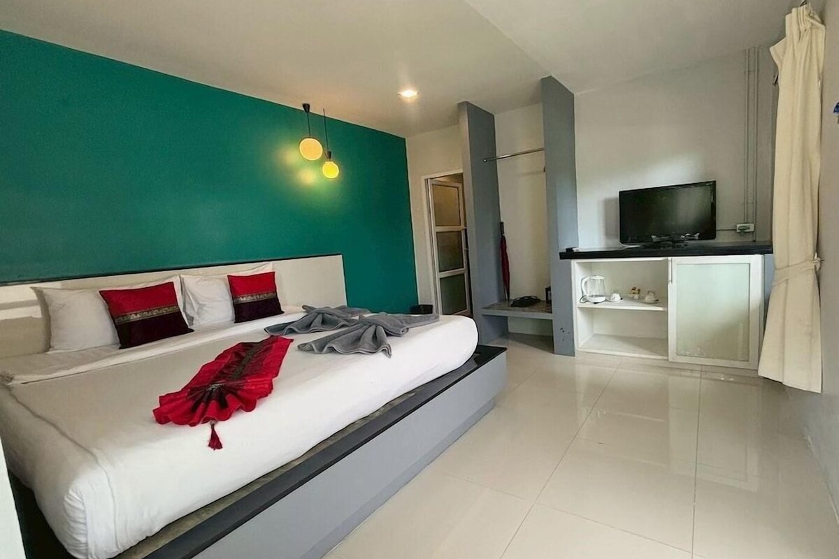 A modern hotel room with a large bed, a television, and a wardrobe.