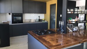 A modern kitchen with dark cabinetry, a wooden countertop, and a built-in oven. - Hotel Internacional (Mendoza)