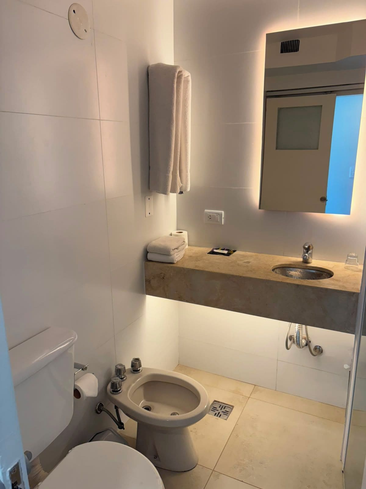 A bathroom with a toilet, bidet, sink, and towel rack.