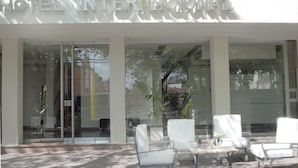 A hotel entrance with a glass facade, outdoor seating area, and a sign reading "HOTEL INTERNACIONAL". - Hotel Internacional (Mendoza)