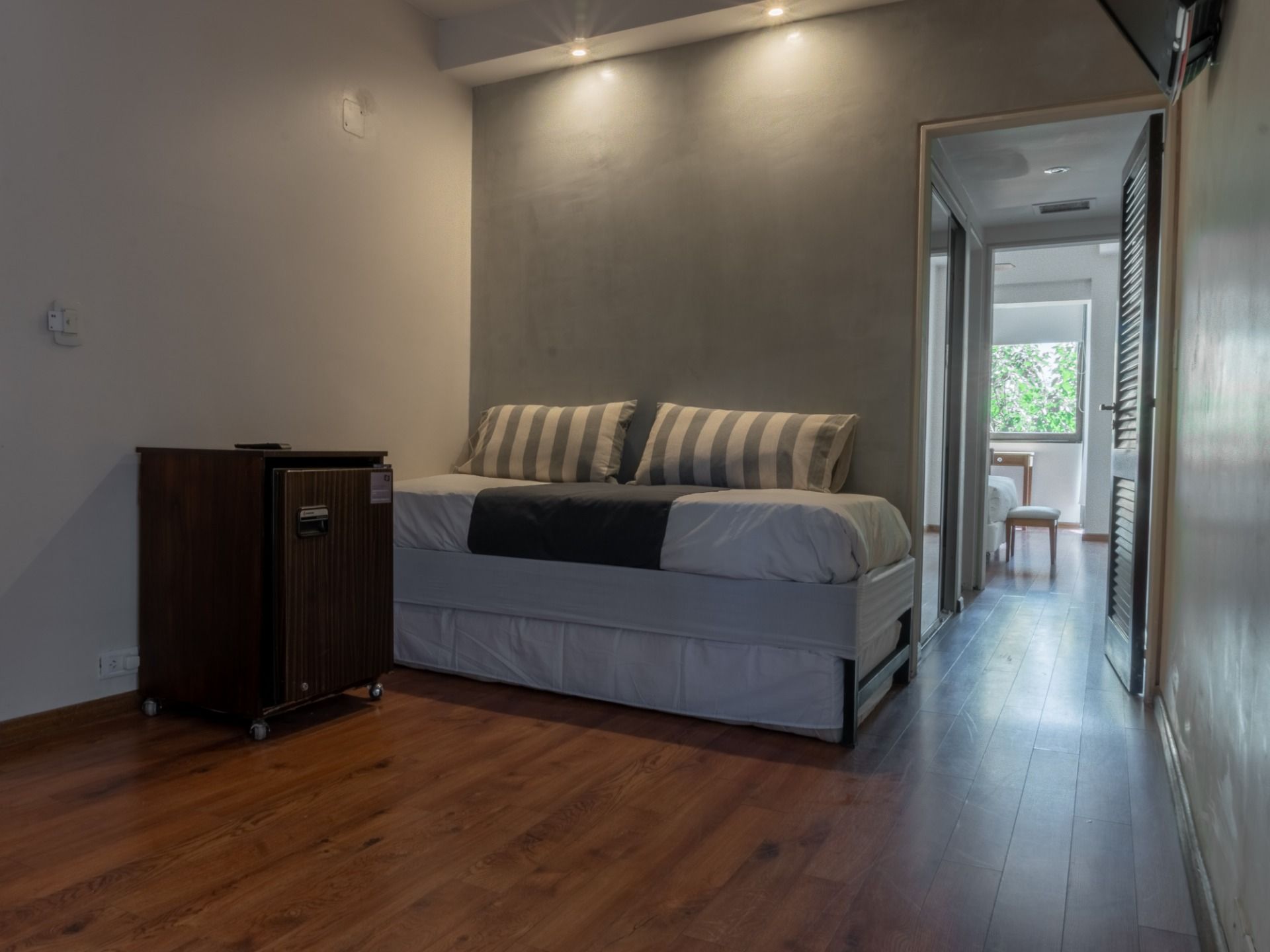 Een slaapkamer met een bed, een houten kast en uitzicht op een balkon.