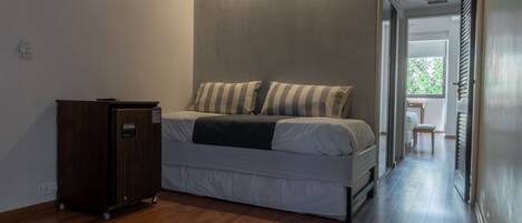 Een slaapkamer met een bed, een houten kast en uitzicht op een balkon.