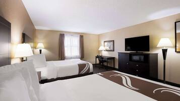 A hotel room with two beds, a desk, a television, and a minibar.
