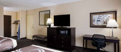 A hotel room with two beds, a desk, a chair, a television, a microwave, and a painting on the wall.