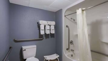 Een badkamer met een toilet, een klein opstapje, een douche met een glazen deur en een handdoekrek met opgevouwen handdoeken.