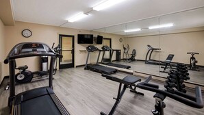 Une salle de sport équipée de tapis de course, de vélos elliptiques et de poids libres.