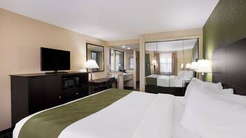 A hotel room with a large bed, a desk, a television, and a mirror.