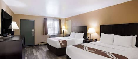 A hotel room with two beds, a desk with a TV, and a window with curtains.