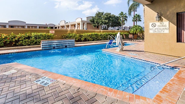 Piscina com trampolim, placa de salva-vidas e aviso de proibição de mergulho.