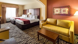 Quarto de hotel com duas camas, um sofá, uma mesa de centro e uma obra de arte emoldurada na parede.