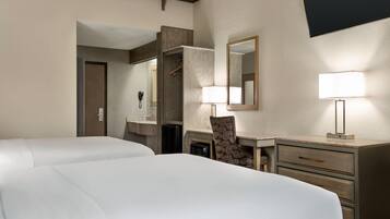 Habitación de hotel con dos camas, un escritorio con una silla, un aparador, un espejo y una lámpara.