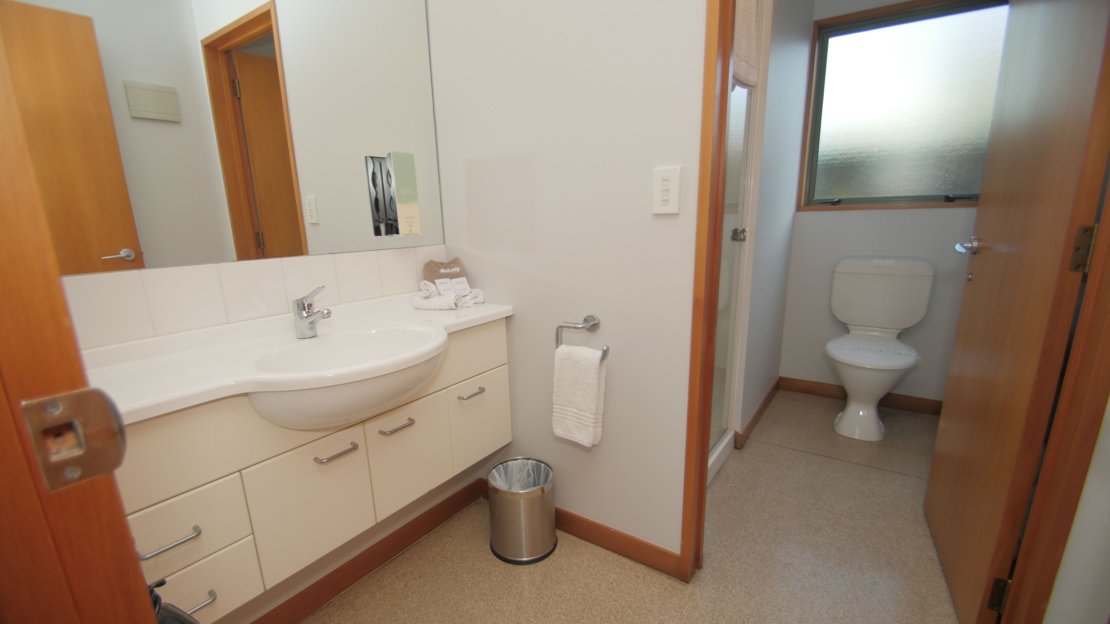 Une salle de bain avec un lavabo, un miroir et des toilettes, le tout de couleur blanche.