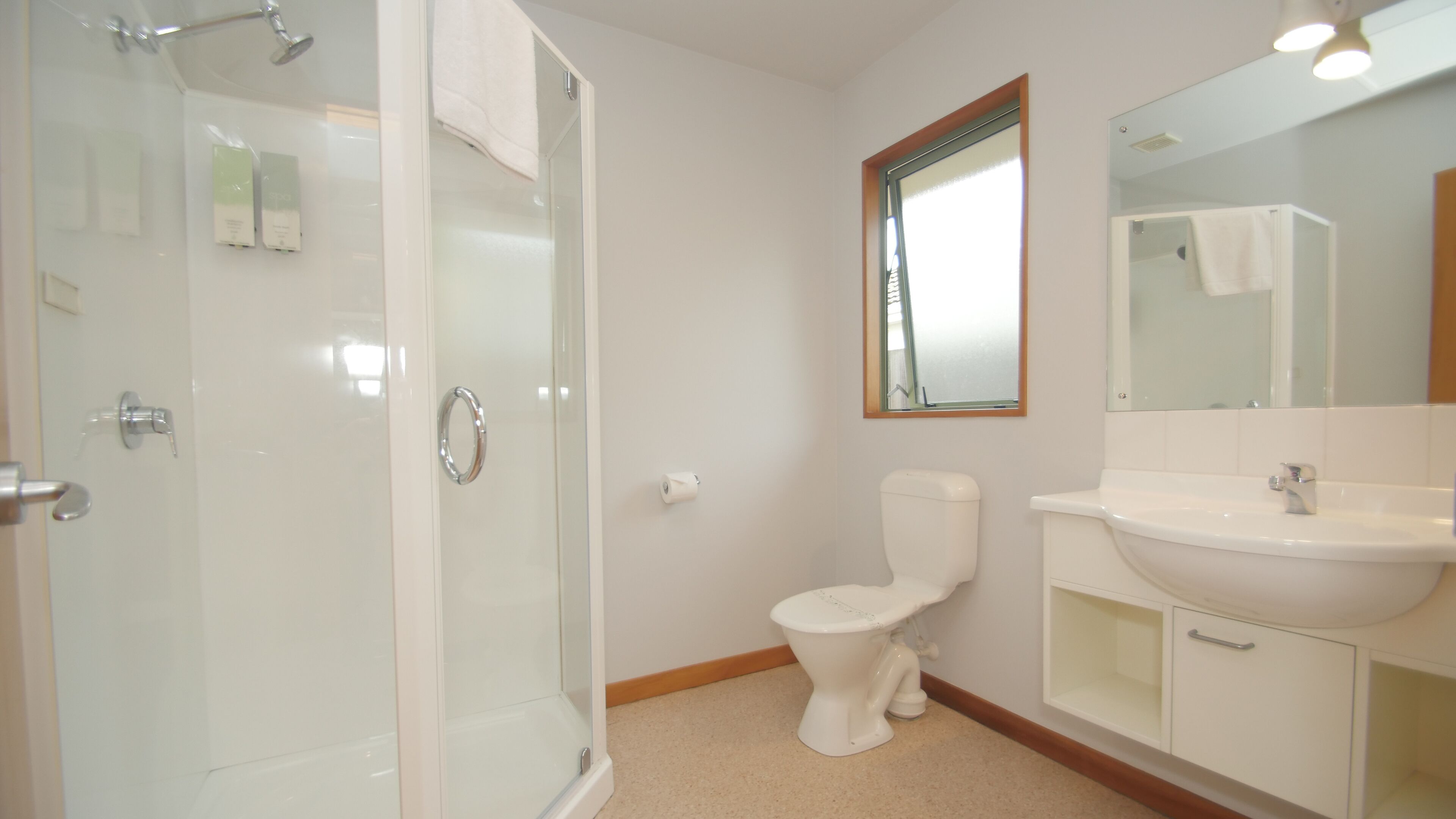 Un baño con cabina de ducha de vidrio, inodoro, lavabo y espejo.