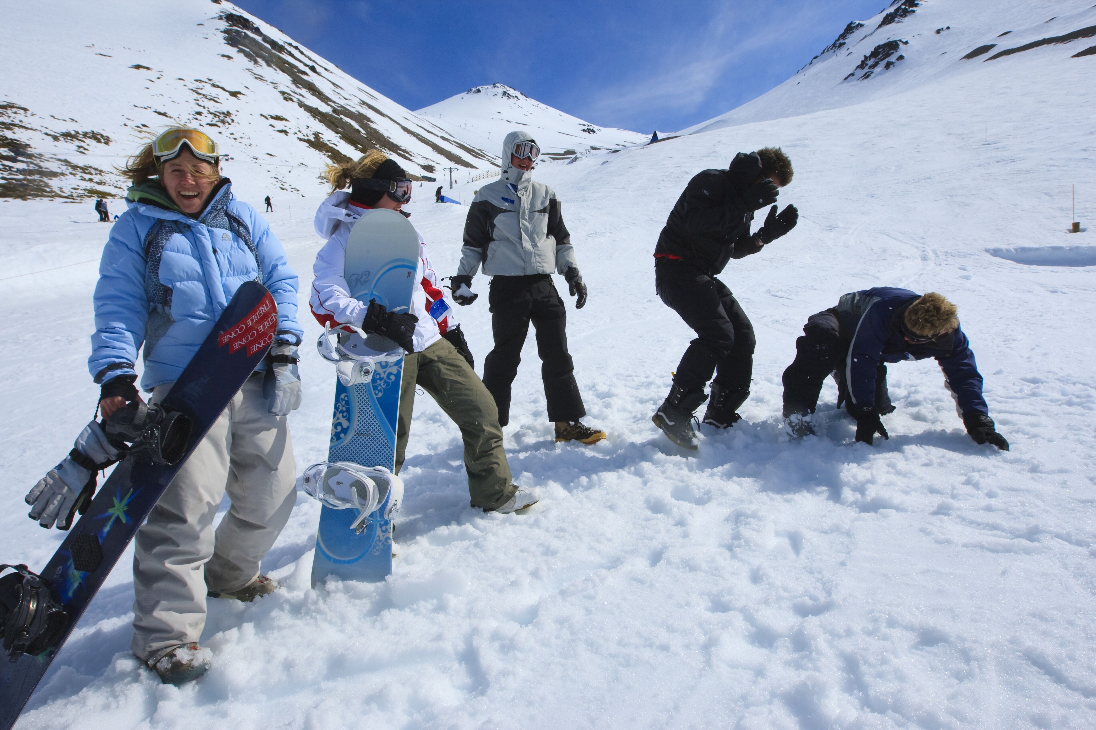 Een groep mensen op een besneeuwde berg met snowboards, wat duidt op een ski- of snowboardgebied.