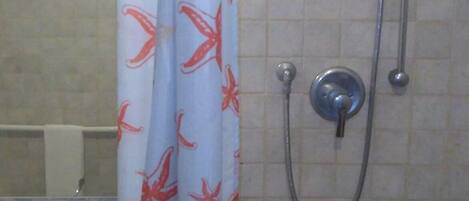 Une salle de bain avec une douche, un lavabo et un mur carrelé.
