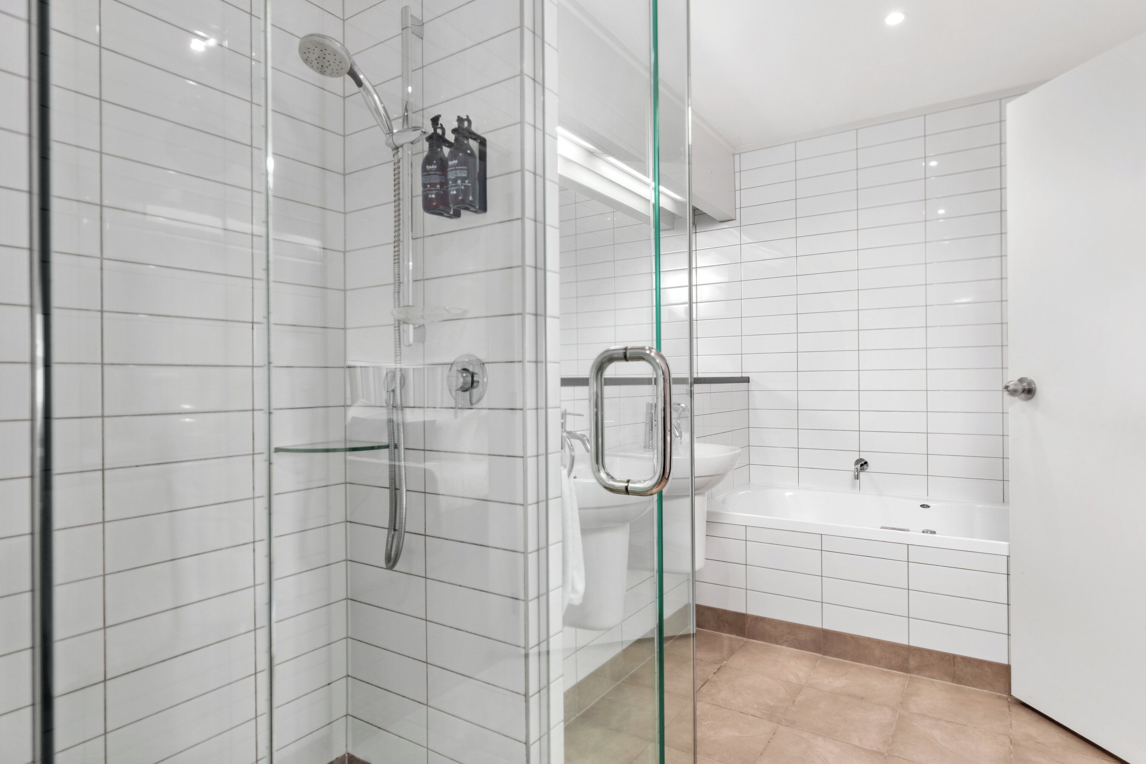 Un baño moderno con cabina de ducha de vidrio, un lavamanos blanco y una bañera.