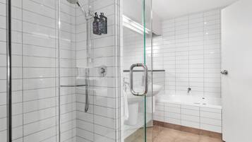 Un baño moderno con cabina de ducha de vidrio, un lavamanos blanco y una bañera.