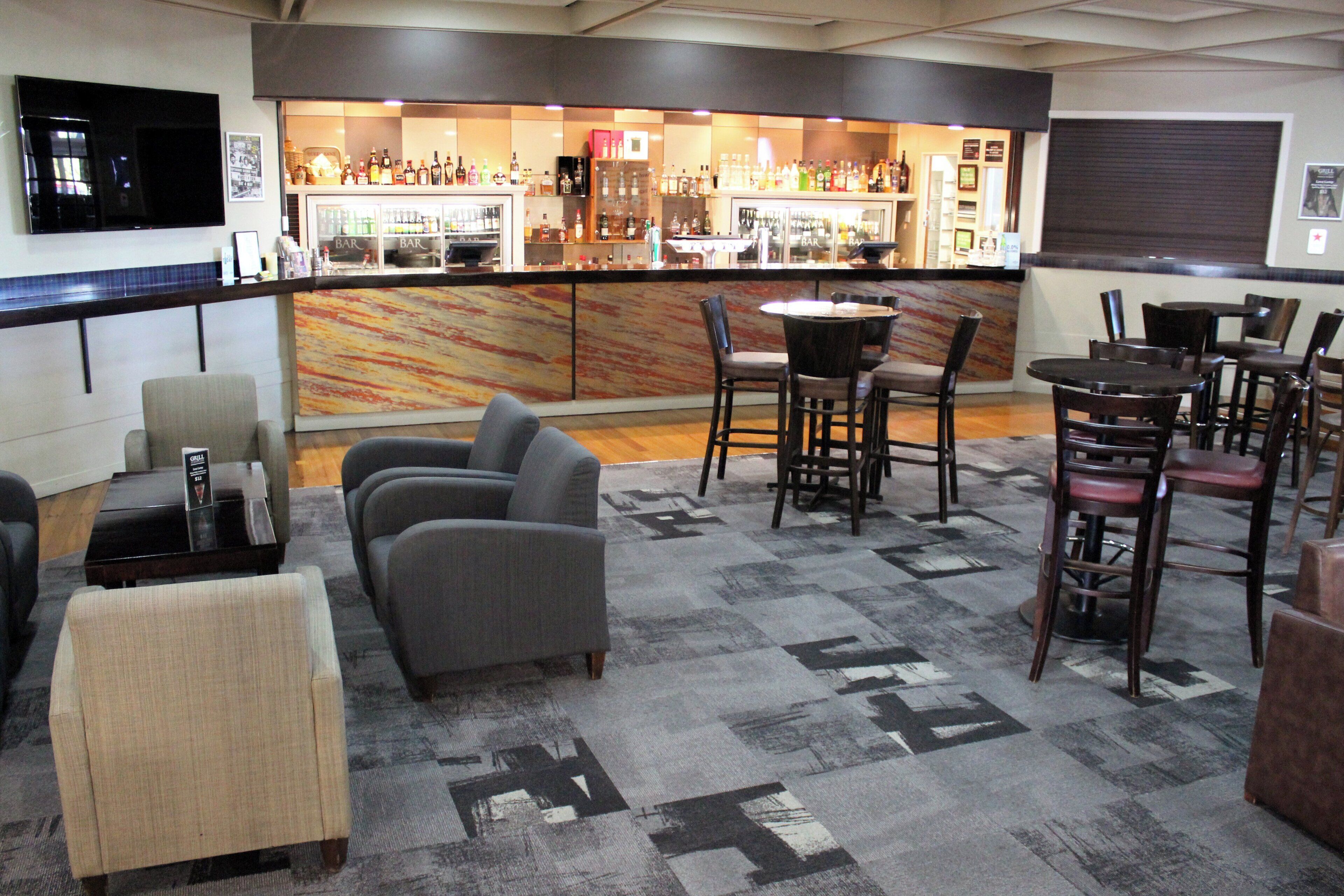 A bar area with a counter, bar stools, and a seating area with sofas and chairs.