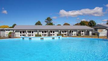 Relax by the hotel's large pool surrounded by lush trees and comfortable lounge chairs.