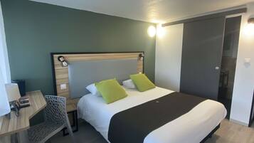 A hotel room with a bed, a desk, and a chair.