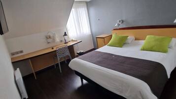 Una habitación de hotel con una cama, un escritorio y una silla.