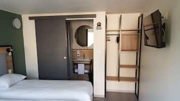 Una habitación de hotel con cama, baño con lavamanos y espejo, y armario.