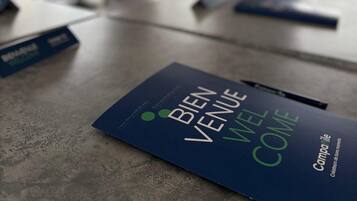 A conference room with a table displaying a brochure titled "Bien Venue Welcome Home."