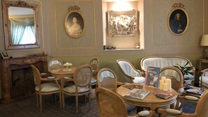Un comedor formal con muebles ornamentados, chimenea y arte clásico.