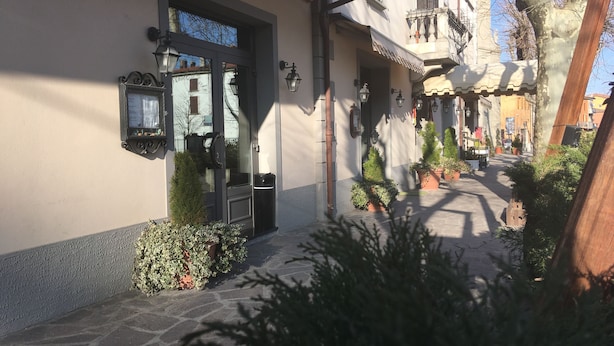 Un edificio con entrada empedrada en piedra, un letrero de metal y un pequeño árbol al frente.